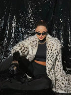 woman sitting and wearing a faux fur coat with an animal print