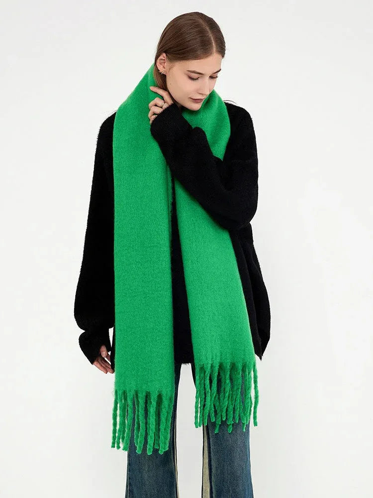 Woman wearing a bright green brushed wool blend scarf with fringe trim draped around her neck.