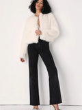 Full body shot of a woman in a white faux fur cropped jacket and black flared jeans.