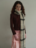 Model wearing a cream and black plaid scarf