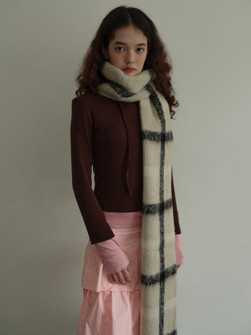 Model wearing a cream and black plaid scarf