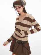 Side view of a woman wearing a brown and beige striped knit hooded sweater with a v-neckline and long sleeves, demonstrating the fit.