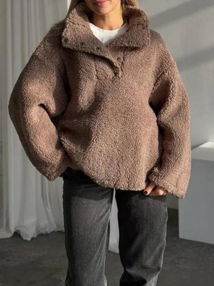 Front view of a woman in a casual brown fleece jacket with dark wash jeans.