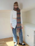 Full body shot of a woman wearing a plaid scarf and jeans.