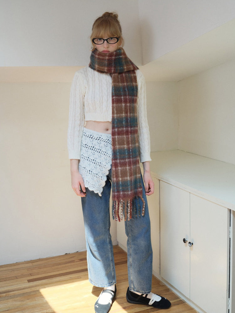 Full body shot of a woman wearing a plaid scarf and jeans.