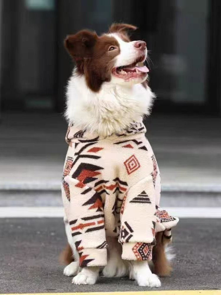 Dog wearing a cream-colored fleece jacket with a black and red geometric pattern.