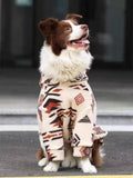 Dog wearing a cream-colored fleece jacket with a black and red geometric pattern.