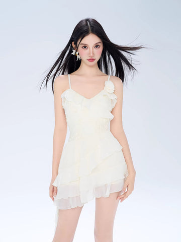 Woman wearing a cream-colored mini dress with spaghetti straps and ruffle detailing.