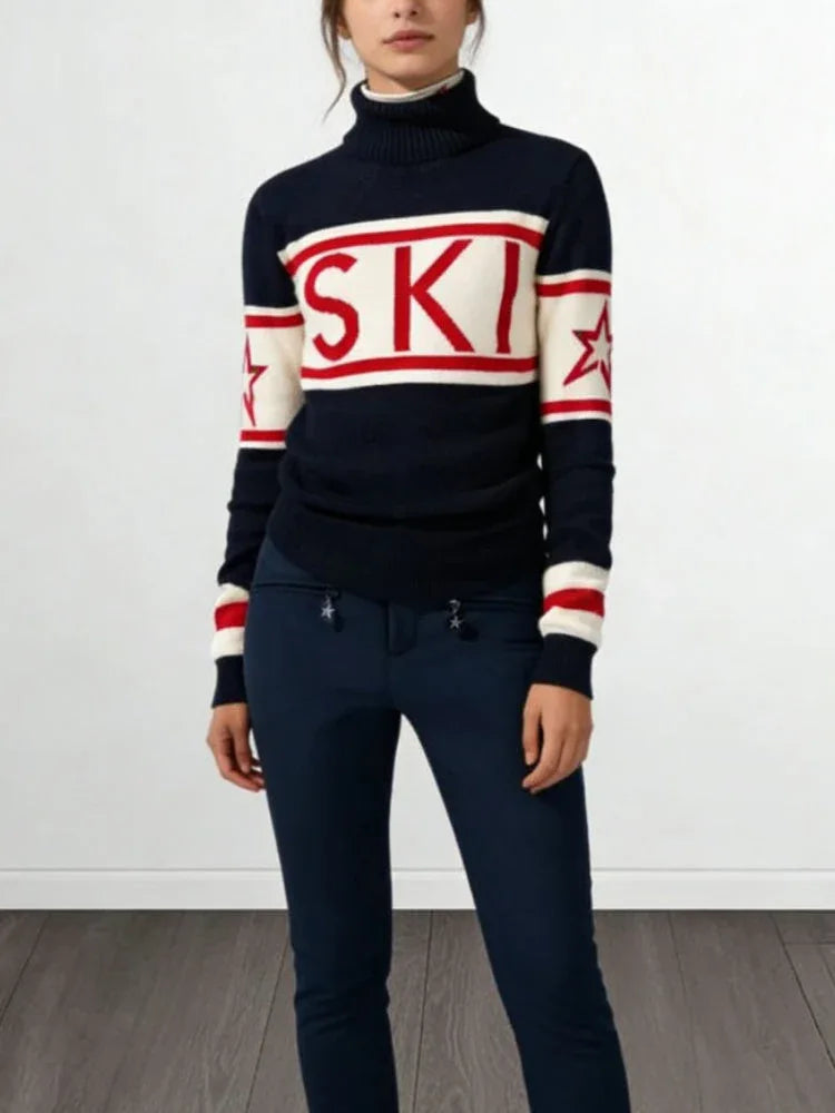 Woman wearing a navy, cream, and red knit turtleneck sweater with 'SKI' graphic and star details