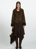 Woman wearing a brown faux suede jacket with shearling trim, a brown midi skirt, and brown boots.
