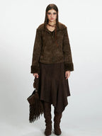 Woman wearing a brown faux suede jacket with shearling trim, a brown midi skirt, and brown boots.