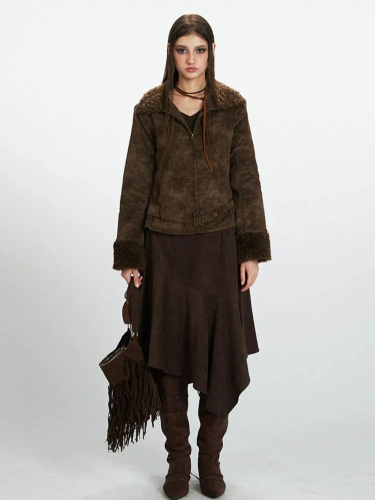 Woman wearing a brown faux suede jacket with shearling trim, a brown midi skirt, and brown boots.