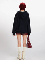 Back view of a woman wearing a navy blue hooded fleece jacket with apple-shaped buttons.
