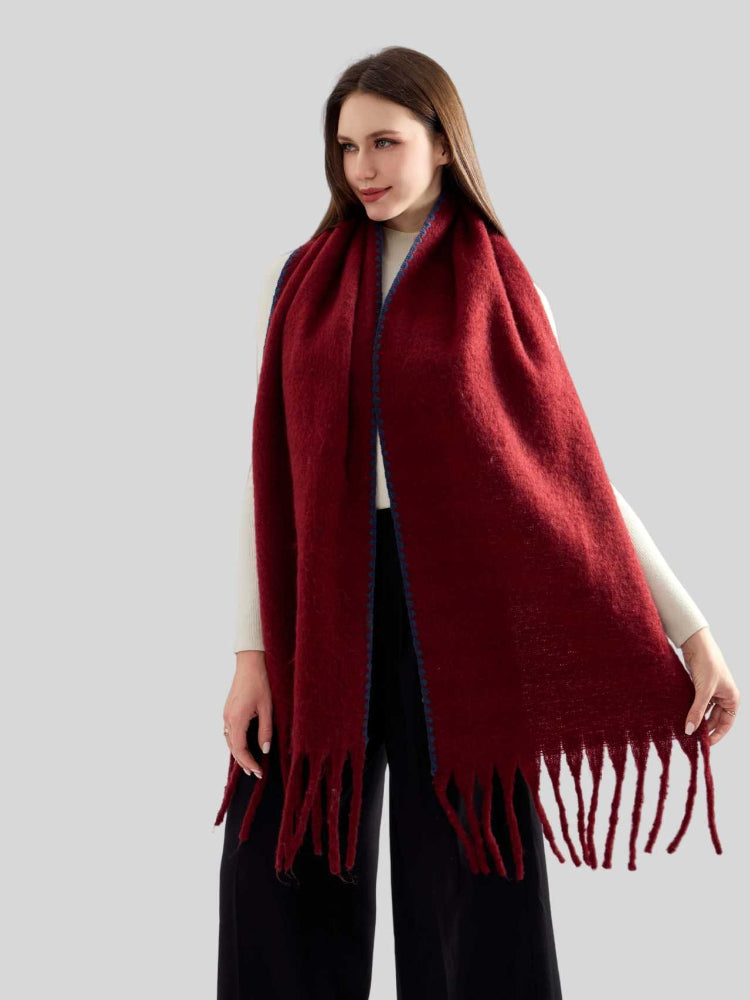 Woman in a white top and black pants, accessorized with a burgundy knit scarf with fringe.