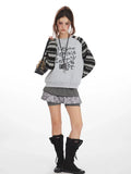 Full body shot of a model in a casual outfit featuring a graphic sweatshirt and shorts.