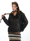 Woman modeling a black faux leather aviator jacket and striped maxi skirt, holding a striped scarf.