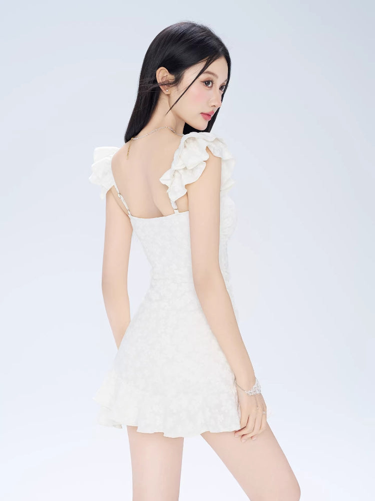 Rear view of a woman in a white jacquard mini dress with ruffled sleeves and a fit and flare silhouette.