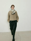 Model walking in a tan jacket and black pants, wearing a cream and black scarf