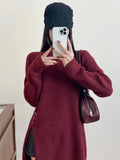 Burgundy oversized knit sweater with crew neck and button details on the side.