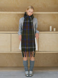 Model showcasing a dark green and blue plaid scarf with fringe.