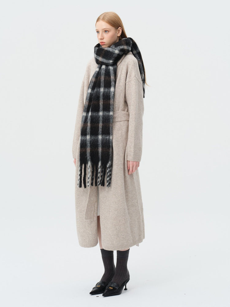 Woman wearing a beige cardigan and a black and white plaid scarf