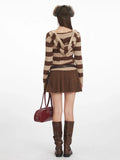 Back view of a woman wearing a brown and beige striped knit hooded sweater with a v-neckline and long sleeves, paired with a brown textured mini skirt and brown boots.
