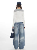 Back view of a woman wearing a white long-sleeve top with a striped collar and blue wide-leg jeans.
