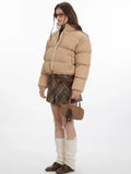 Side view of a woman in a beige cropped puffer jacket.