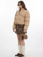 Side view of a woman in a beige cropped puffer jacket.