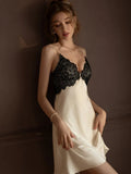 Woman wearing a cream-colored satin slip dress with black lace trim, in a relaxed pose.