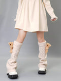 Cream cable knit leg warmers with teddy bear embellishments, worn with a cream dress and white platform sneakers.