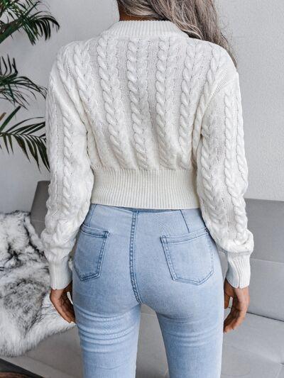 Back view of a woman wearing a white cropped cable knit sweater and light wash jeans