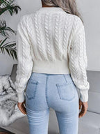 Back view of a woman wearing a white cropped cable knit sweater and light wash jeans