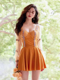 Woman wearing a mustard yellow one-piece swimsuit with sheer bishop sleeves and tribal trim