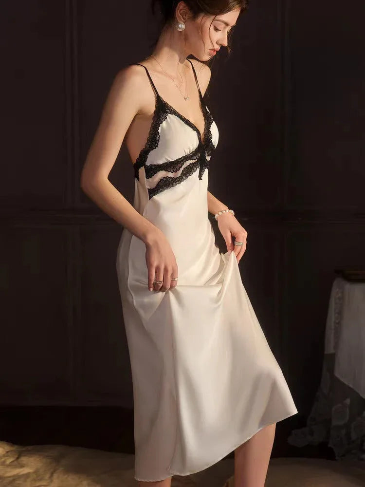 Side profile of a woman in a white satin slip dress with black lace trim
