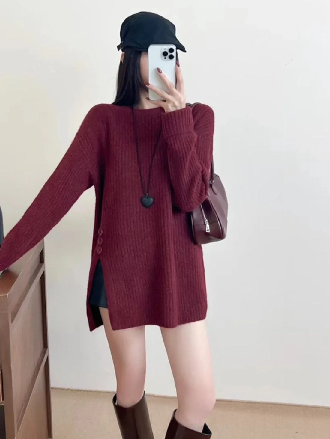 Woman wearing a burgundy knit tunic with side slits and button details.