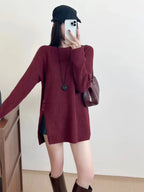 Woman wearing a burgundy knit tunic with side slits and button details.