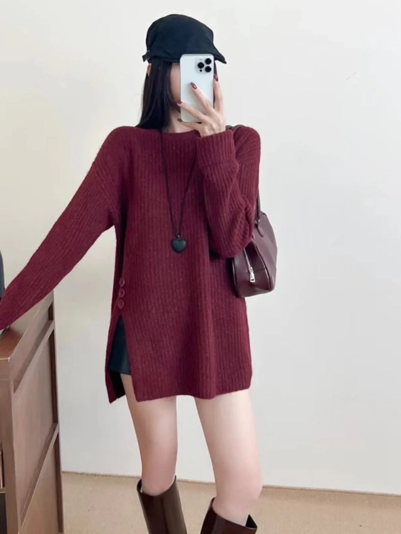 Woman wearing a burgundy knit tunic with side slits and button details.