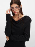 Close-up of a woman adjusting her sunglasses while wearing a black long-sleeve asymmetrical knit sweater