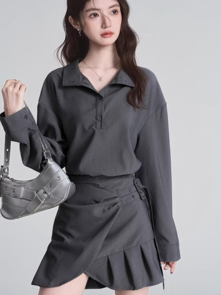 Woman holding a silver handbag while wearing a grey top and skirt