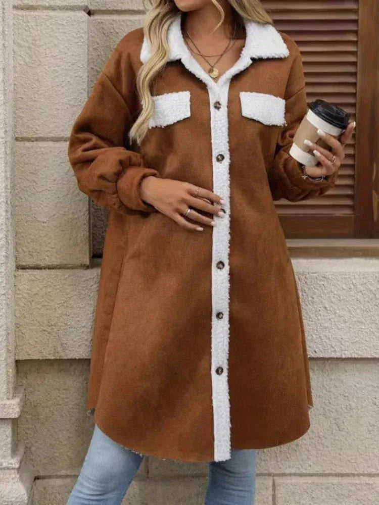 Front view of a woman in a brown shirt jacket with sherpa collar and cuffs, holding a coffee cup.