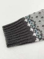 Close-up of the ribbed cuff of a grey knit sweater