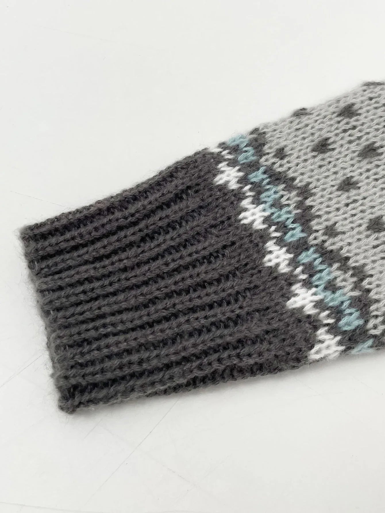 Close-up of the ribbed cuff of a grey knit sweater