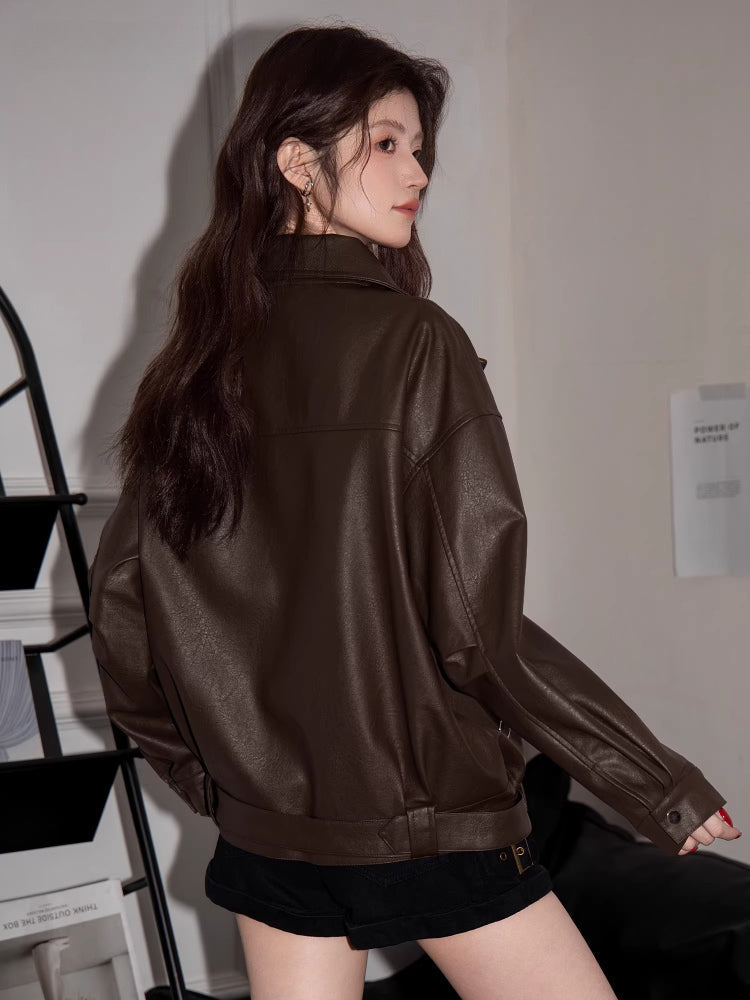 Back view of a woman in a brown faux leather moto jacket.