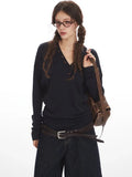 Woman with braided hair wearing a navy long-sleeve top and denim culottes.