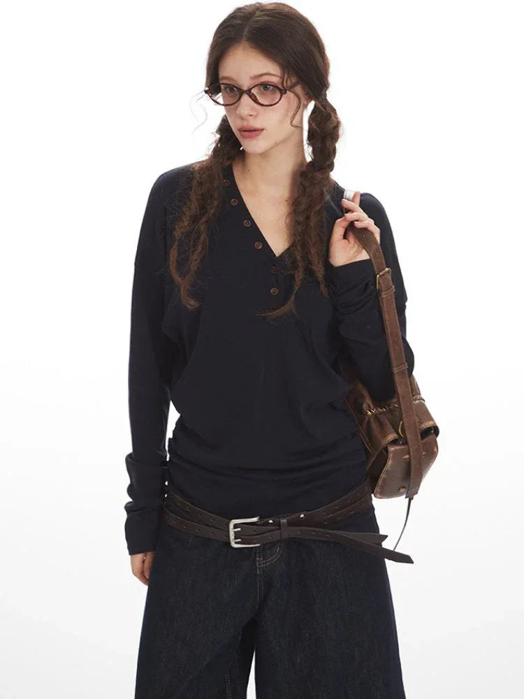 Woman with braided hair wearing a navy long-sleeve top and denim culottes.