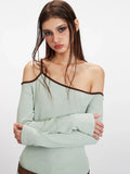 Detailed shot of the light green ribbed knit one-shoulder top worn by a model.