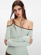 Detailed shot of the light green ribbed knit one-shoulder top worn by a model.