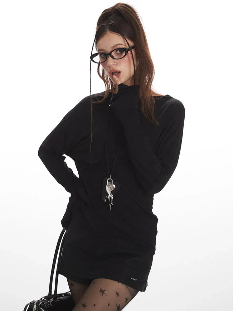 Model posing with a hand near her face, highlighting the black long-sleeved top and accessories.