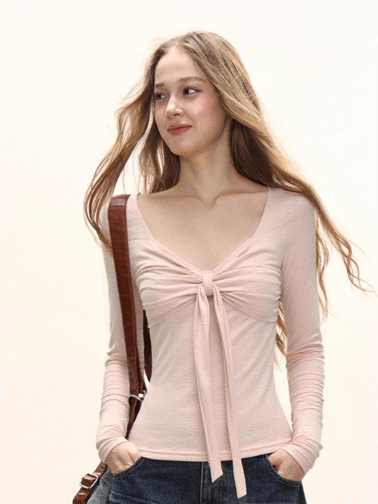 Model wearing a light pink long sleeve tie front top